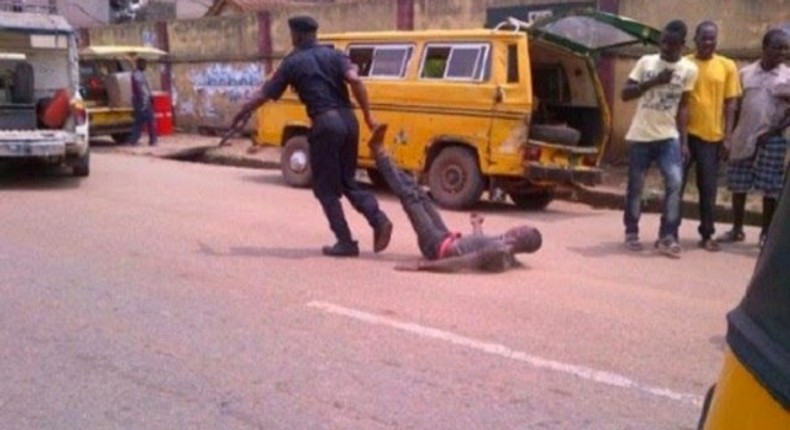 A policeman drags a civilian while some pedestrians kept their distance.