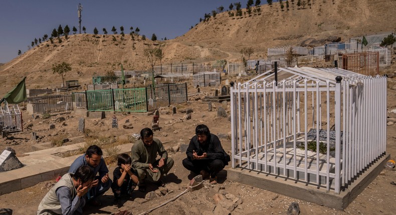 In this Monday, Sept. 13, 2021 file photo, the Ahmadi family pray at the cemetery next to family graves of family members killed by a US drone strike, in Kabul, Afghanistan.
