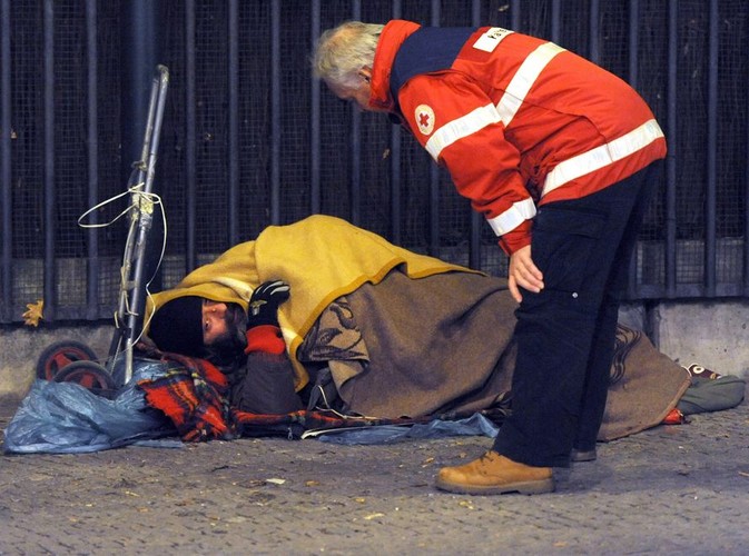 Pracownik Czerwonego Krzyża oferuje pomoc bezdomnemu nocującemu na ulicy w Berlinie