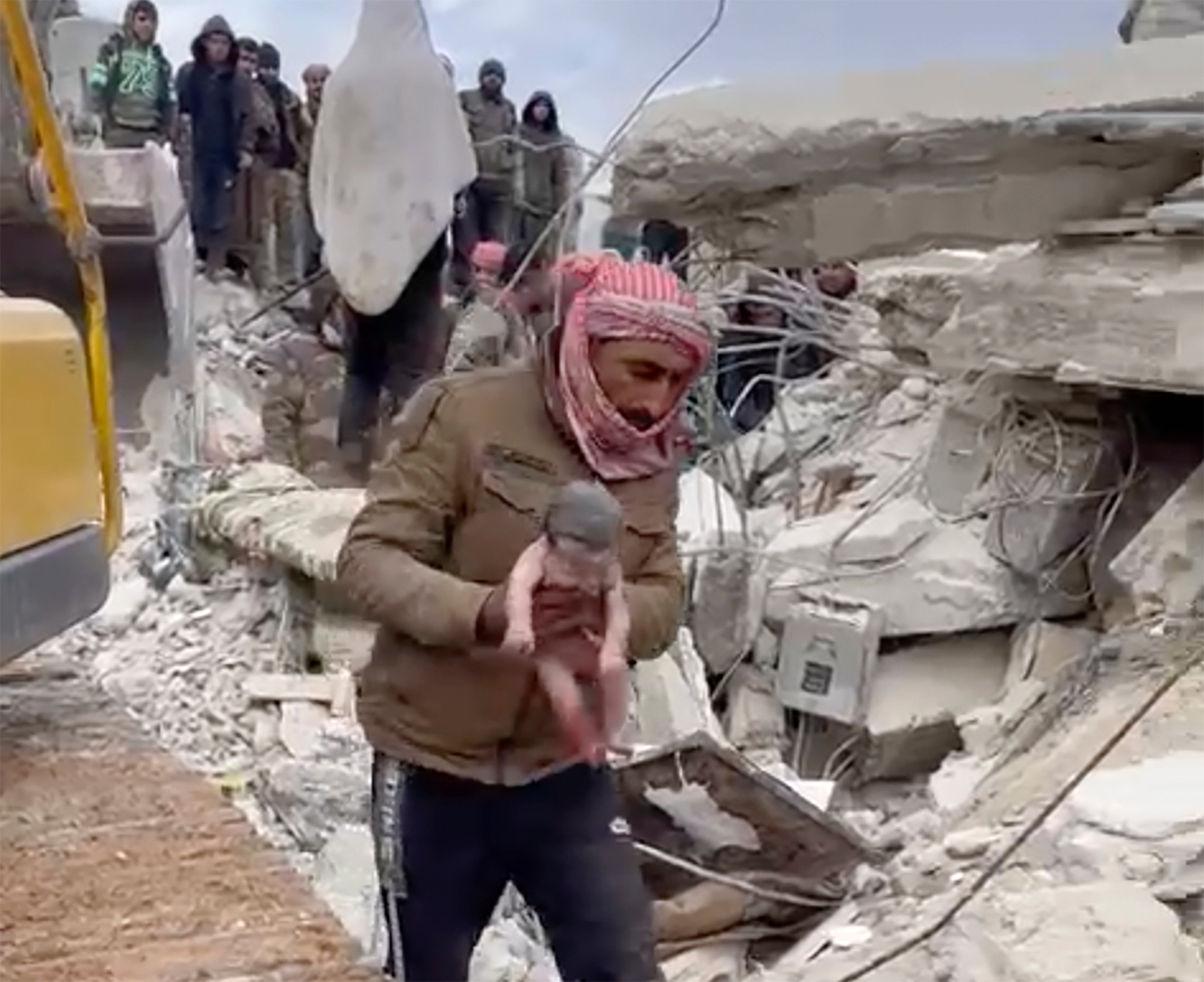 Záchranár drží novorodenca, ktoré vytiahli z trosiek budovy, ktorá sa zrútila v dôsledku ničivého zemetrasenia v meste Džindíras v provincii Aleppo na severe Sýrie v utorok 7. februára 2023.