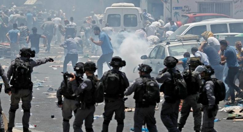 Palestinian worshippers run for cover as Israeli forces fire tear gas following protest prayers held outside Jerusalem's Old City on July 21, 2017, after police denied entry to men under 50