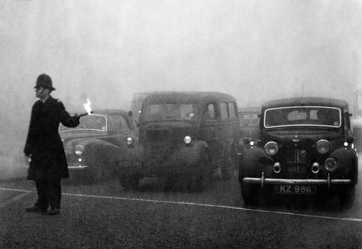 Policeman on point duty seen here using flares to guide the traffic during a heavy smog in London. 8