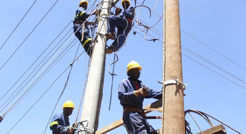 Kenya Power workers install concrete pole