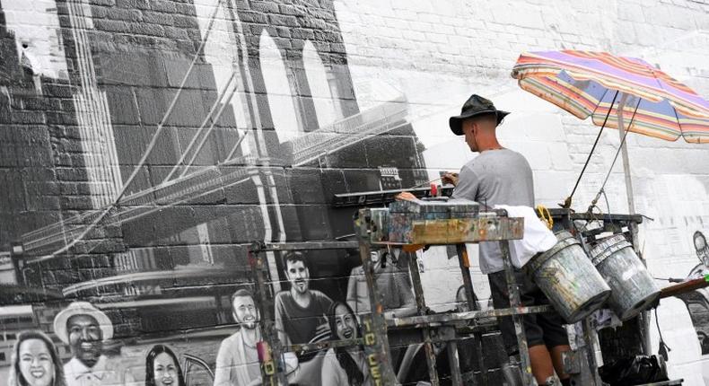 Liam Williams, artist at Colossal Media, paints an ad on the side of Colossal Media's office building in New York