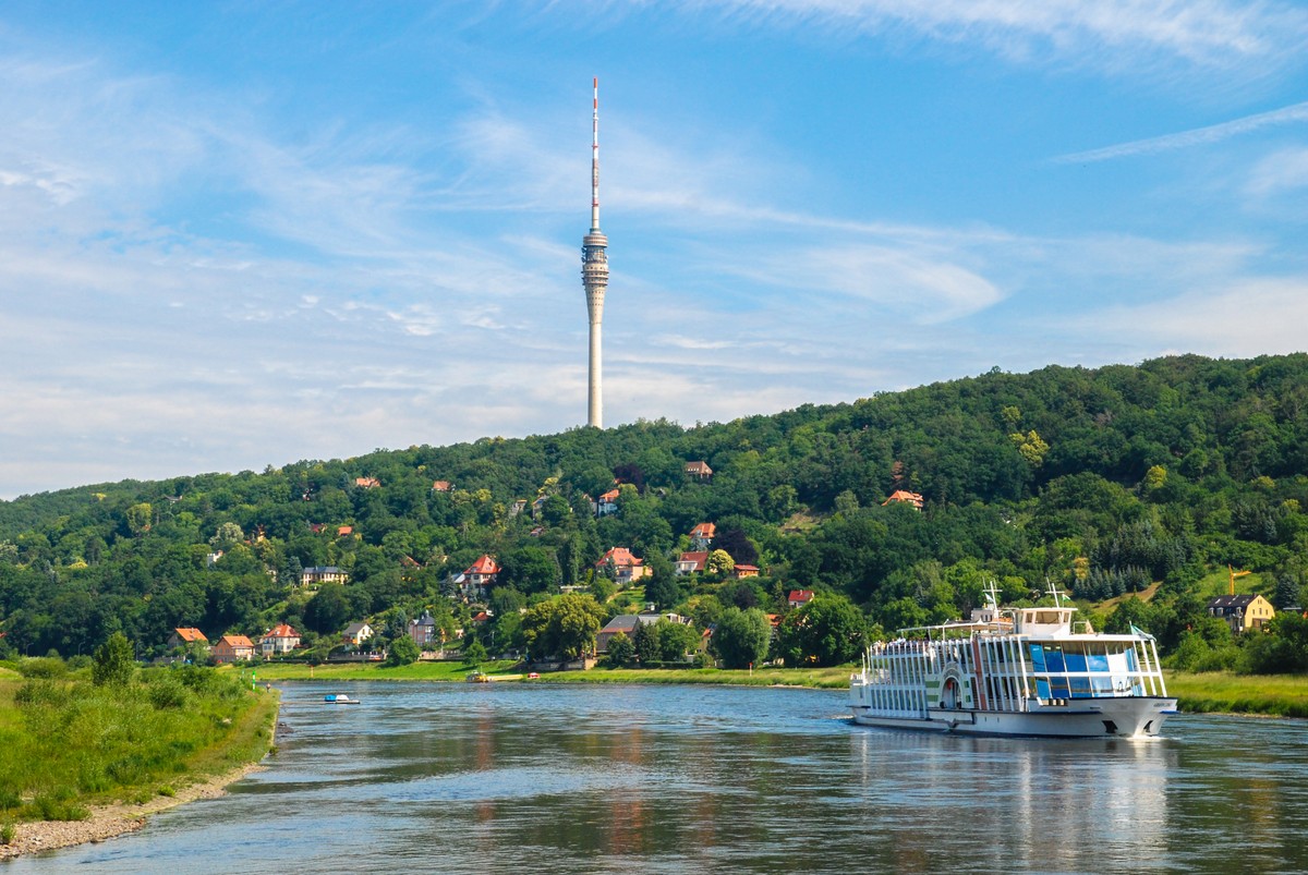 Statek płynący po rzece na tle zieleni.
