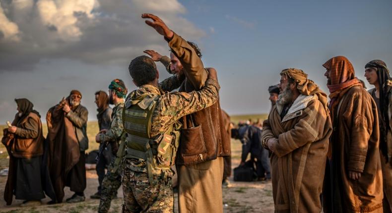 Men suspected of being Islamic State group fighters are searched after leaving the jihadists' last holdout of Baghouz in Syria