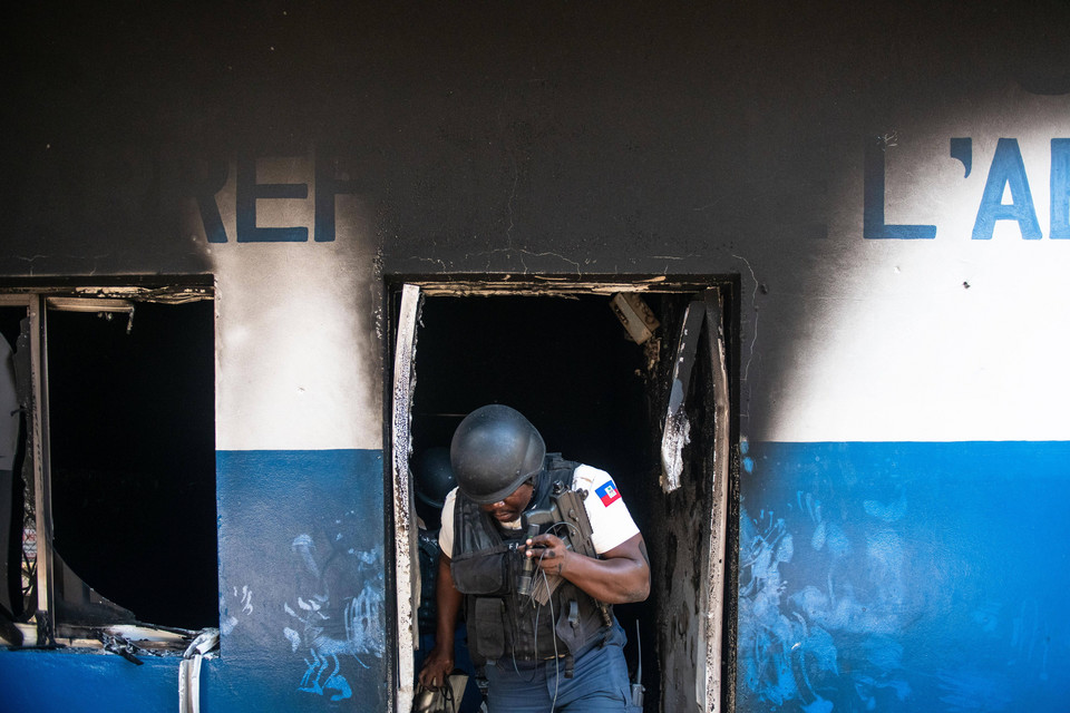 Policjant wychodzi ze zniszczonego budynku komendy w Port-au-Prince, którą gangsterzy podpalili 4 marca 2024 r. 