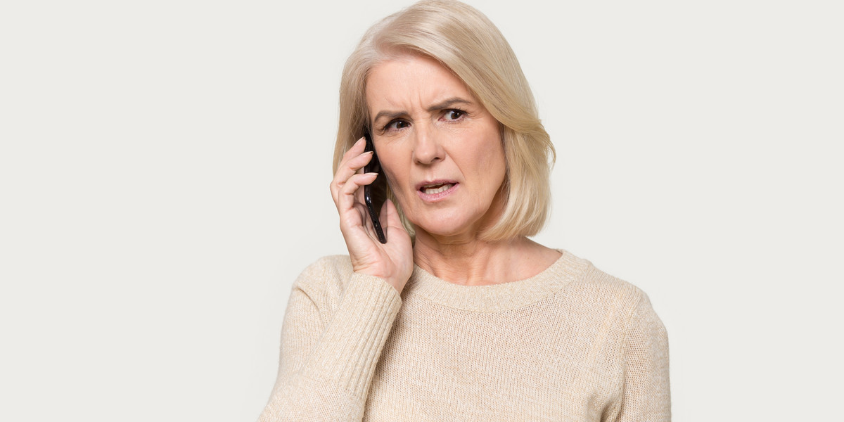 Mature lady isolated on grey background use smartphone talking