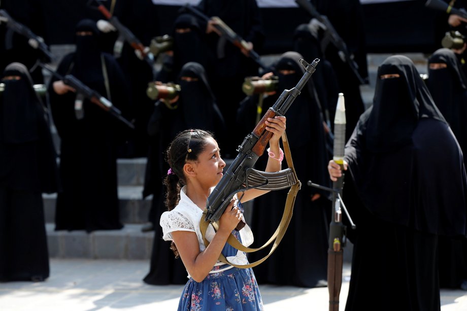 A girl holds a rifle in front of women loyal to the Houthi movement taking part in a parade to show support to the movement in Sanaa, Yemen September 6, 2016.