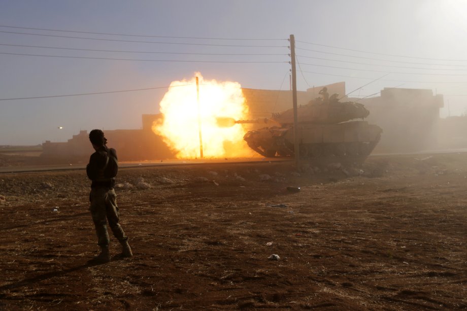 A rebel fighter stands near a Turkish tank as it fires towards Guzhe village, northern Aleppo countryside, Syria, October 17, 2016.