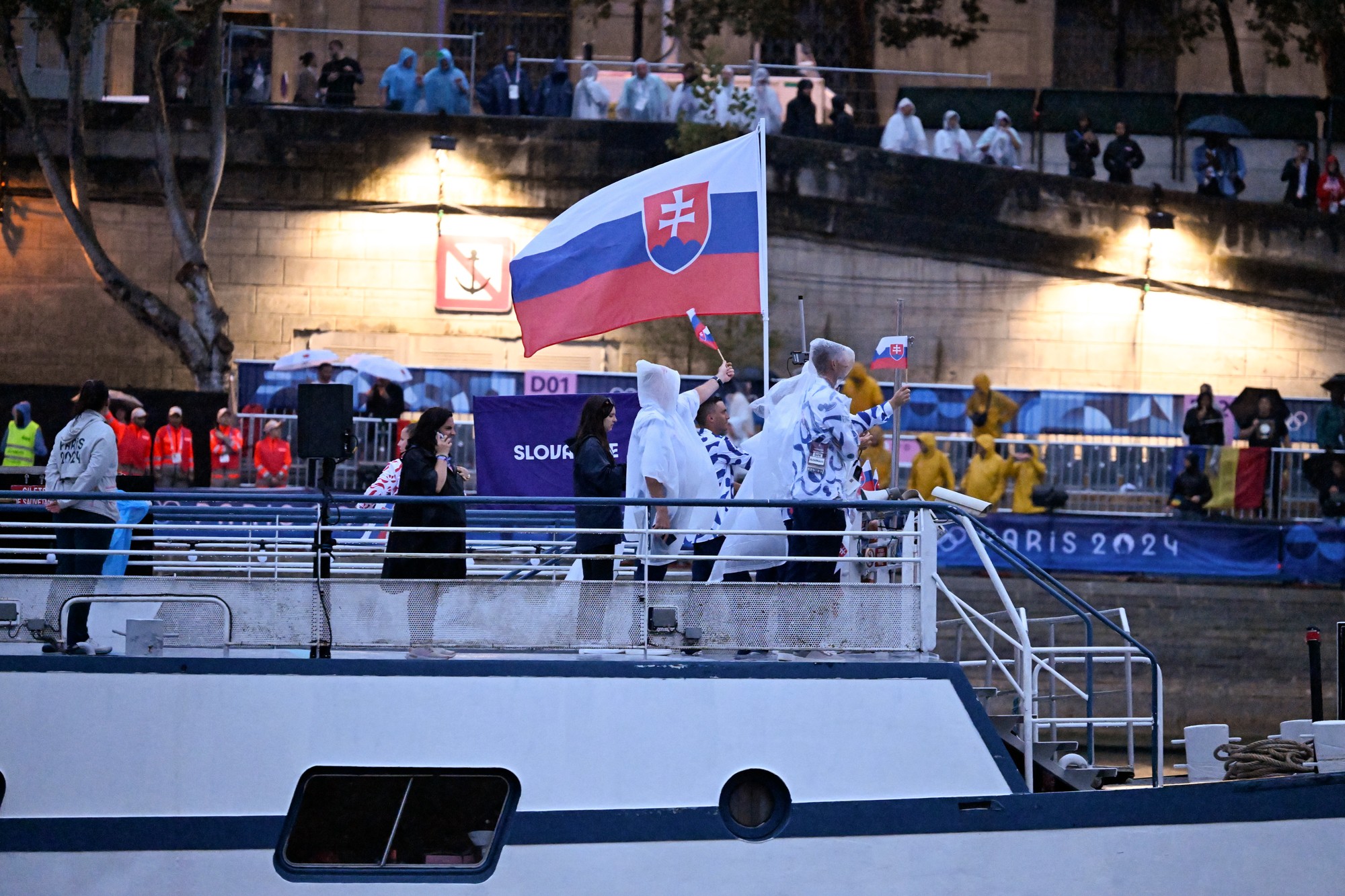 Vlajkonosiči slovenskej výpravy - vodní slalomári Jakub Grigar a Zuzana Paňková sa vezú na lodi po rieke Seina počas otváracieho ceremoniálu XXXIII. letných olympijských hier v Paríži 26. júla 2024.