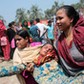 Women help a relative of a garment worker, who went missing in the Rana Plaza collapse, after she fa