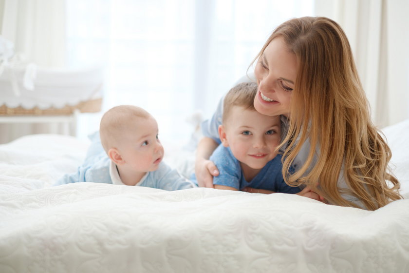 Happy middle aged mother with her children in a bed