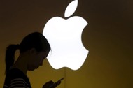 File photo of a woman looking at the screen of her mobile phone in front of an Apple logo outside an