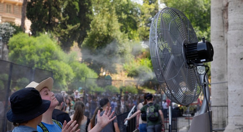 Tourists cool off near a fan as they queue to enter Rome's Colosseum on July 18. Gregorio Borgia/AP