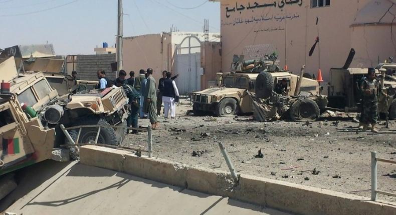 Afghan security personnel inspect the site of a suicide attack near the main police headquarters in Lashkar Gah, capital of Helmand province