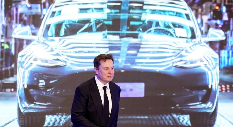 Tesla CEO Elon Musk walks in front of a Model Y image in Shanghai.

