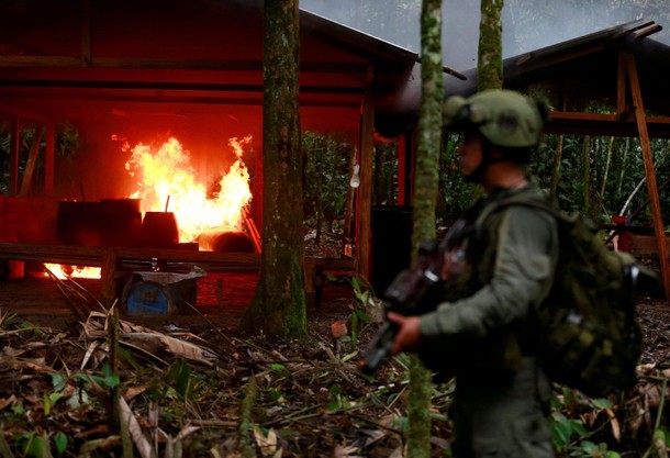 A Colombian anti-narcotics policeman stands guard after burning a cocaine lab, which police said bel