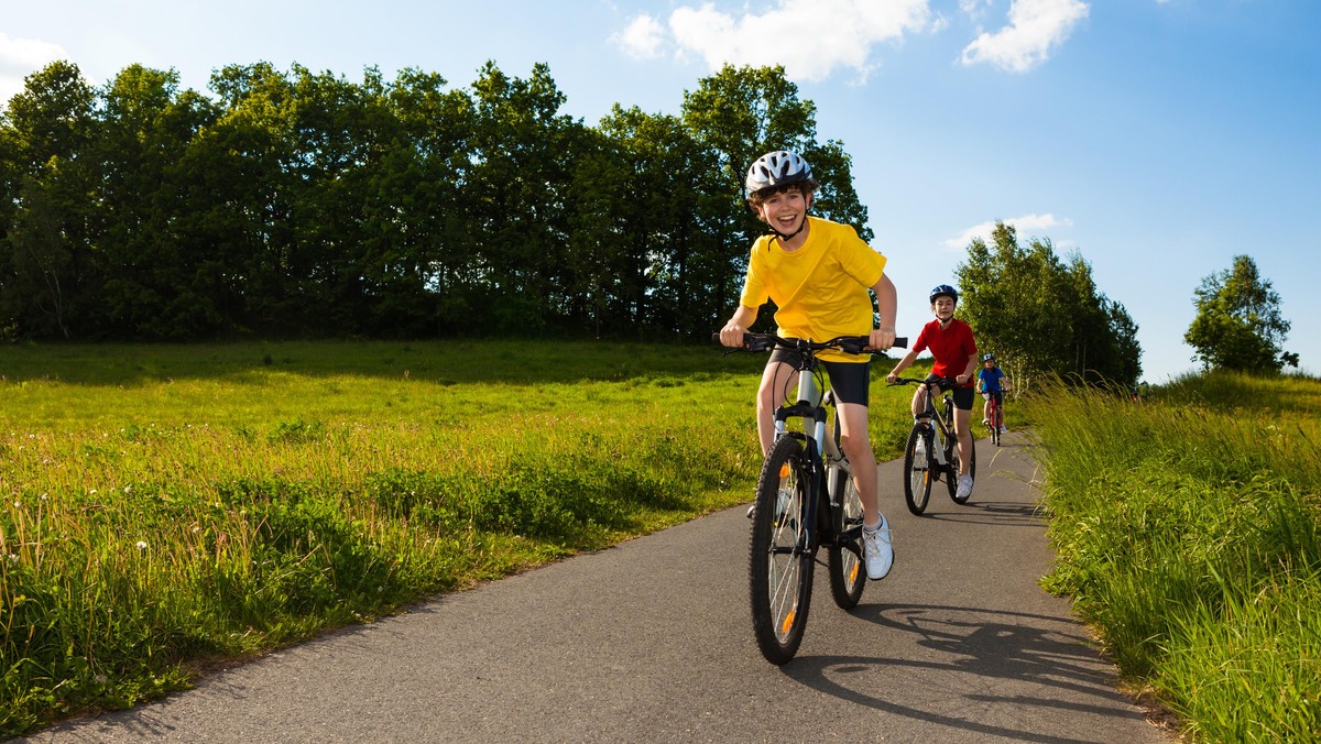 A happy family riding their bikes on a country road