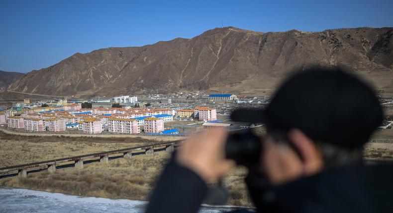 A man with a pair of binoculars looking toward the North Korean city of Namyang from the city of Tumen in Jilin province, northeast China.Pedro PARDO / AFP via Getty Images