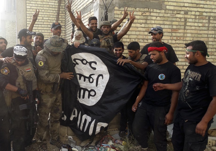 Iraqi security forces with an ISIS flag they pulled down at the University of Anbar, in Anbar province, July 26, 2015.