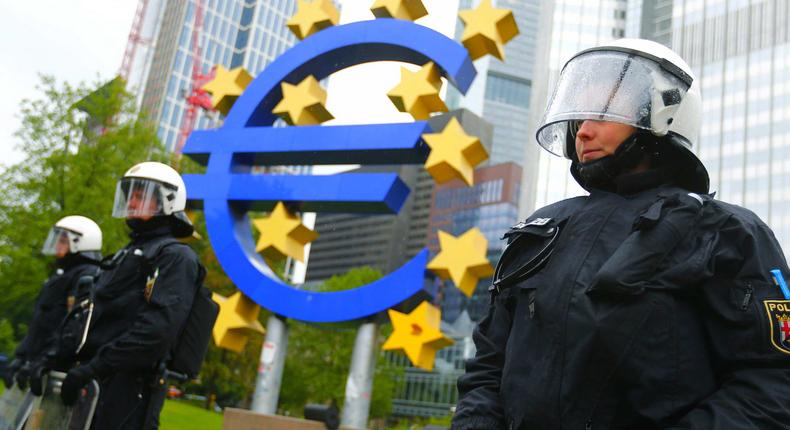 Riot police stand by the European Central Bank's euro sculpture ahead of a protest.