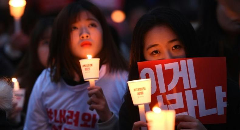 Protesters hold candles and banners calling for the resignation of South Korea's President Park Geun-Hye during a rally in Seoul on November 19, 2016