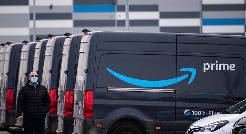 An Amazon employee walks by an Amazon Prime delivery truck in the company's premises in Brandizzo, near Turin, March 22, 2021