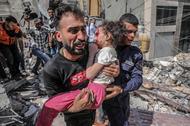 Palestyńczyk ucieka z ranną córką ze zniszczonego domu po izraelskim nalocie, Gaza, 16 maja 2021 r.