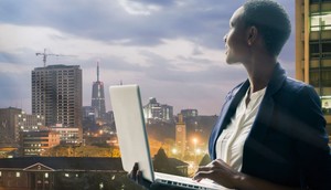 Businesswoman holding her laptop by the Nairobi city skyline