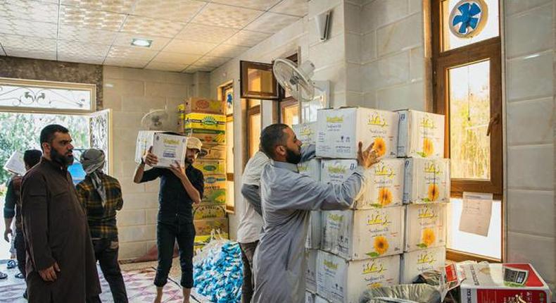 In this Friday, June 19, 2015 photo provided by a website of the Islamic State group, IS members prepare foodstuff to be handed over to the poor during the Muslim holy month of Ramadan in Mosul, northern Iraq. The IS shows two faces to the millions who live under its rule in Iraq and Syria: handing out food and alms to the poor to tout their adherence to the month's spirit of compassion while meting out sharp punishment to anyone caught breaking the daily fast. 