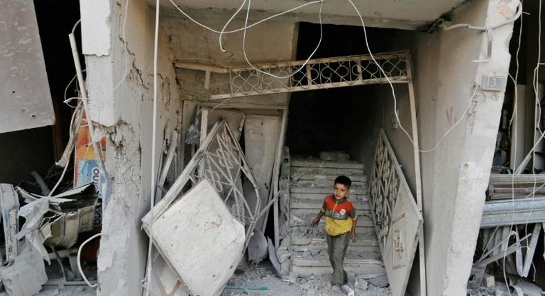 A Syrian child walks out of damaged building following an air strike on the rebel-held town of Arbin, east of the capital, on July 22.