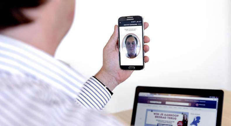 A picture shows a man using a smartphone with an app that allows online payments using biometric authentication.