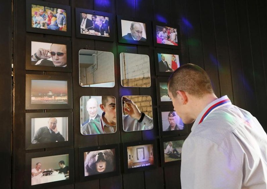 A man looks at his reflection in a mirror decorated with portraits of Vladimir Putin in the "President Cafe" in Krasnoyarsk, Siberia, Russia, April 7, 2016.