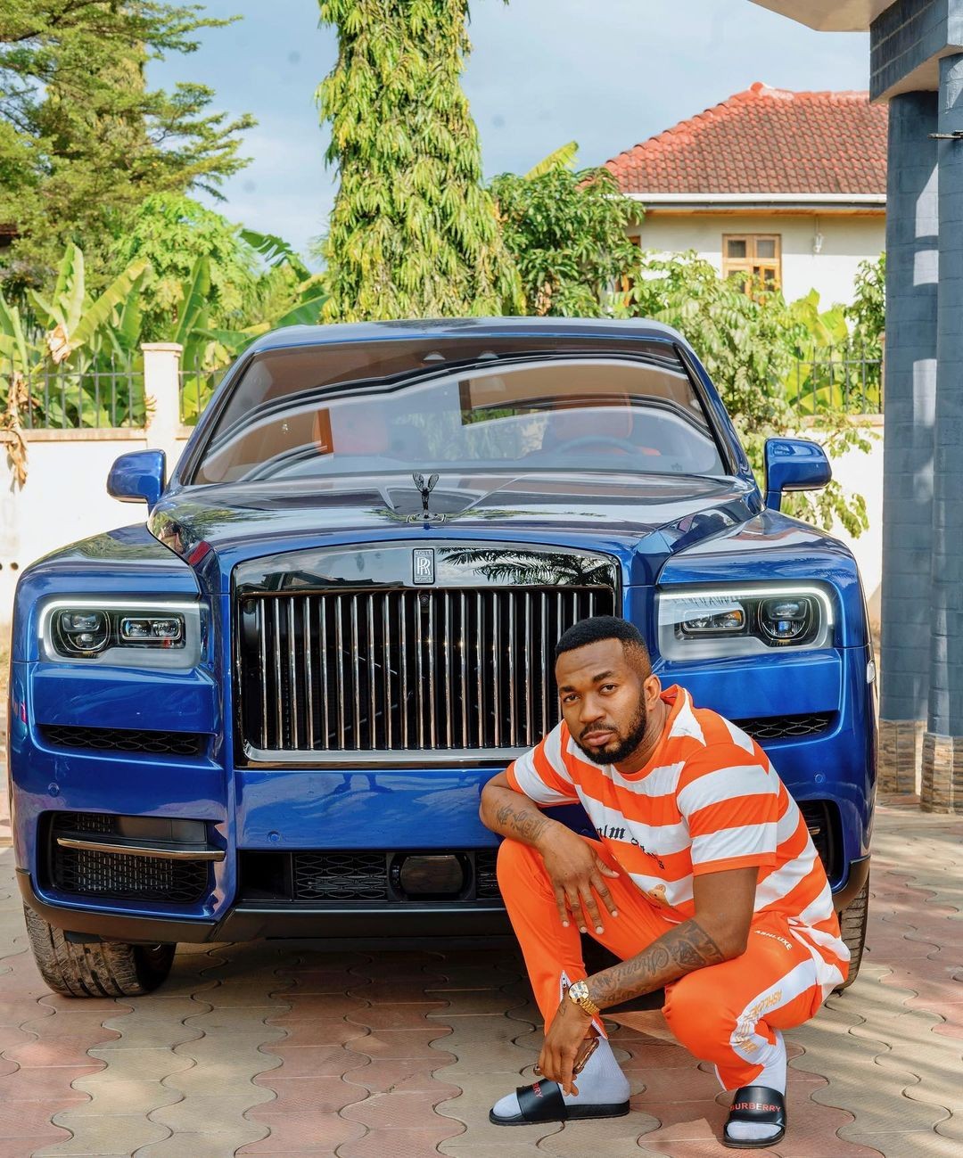 Diamond's brother Romy Jons posing in front of The 2021 Rolls-Royce Cullinan