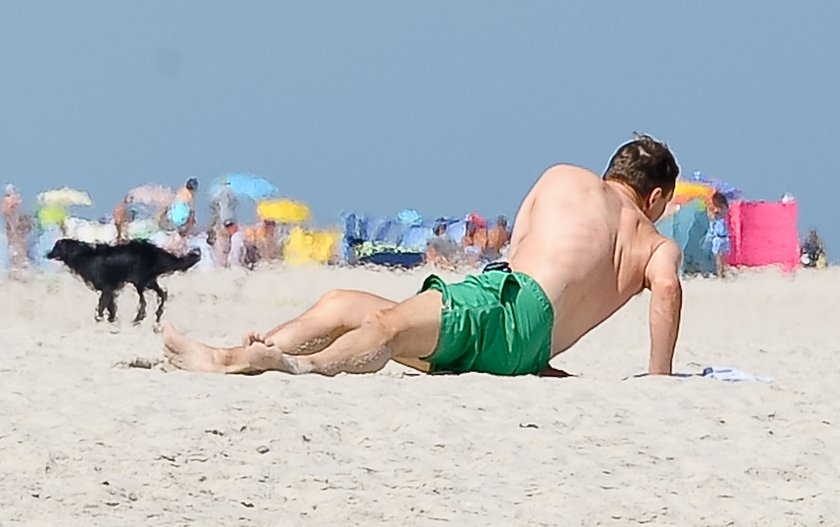 Radosław Sikorski na plaży ćwiczy brzuszki 