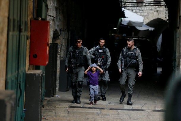 Israeli border policemen escort a boy away from a blocked alley after a stabbing attack inside the o