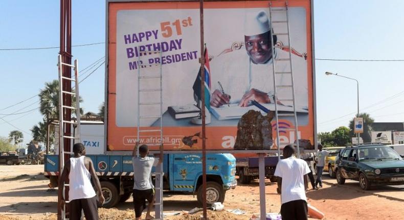 Workers prepare to remove an electoral poster for longtime Gambian leader Yahya Jammeh, after he conceded defeat in a presidential poll