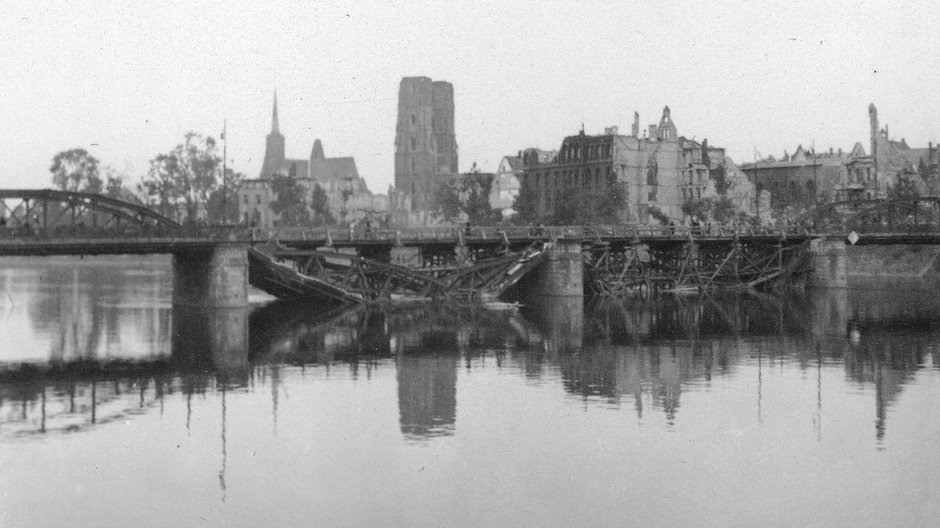 Wrocław, panorama Ostrowa Tumskiego. Na pierwszym planie Odra i uszkodzony most Lessinga (widoczne dwa zniszczone przęsła). W głębi zabudowa Ostrowa Tumskiego, m.in. archikatedra św. Jana Chrzciciela, kościół św. Krzyża i św. Bartłomieja (z lewej). Widoczne zniszczenia wojenne.