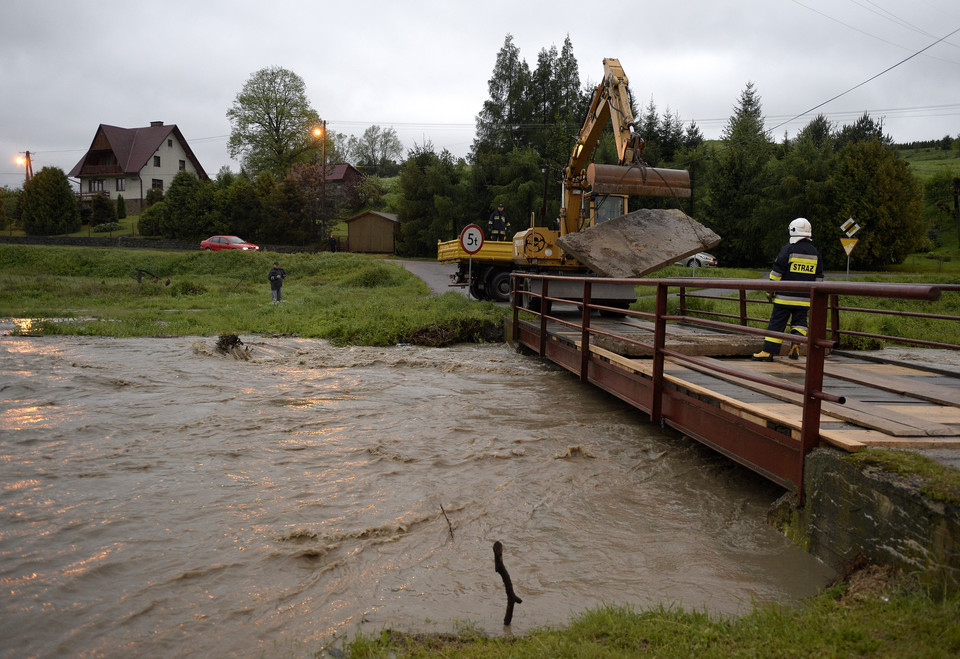 Strażacy obciążają betonowymi płytami most na wezbranej rzece Stupnica w Birczy, chcąc uchronić go przed zerwaniem przez wodę