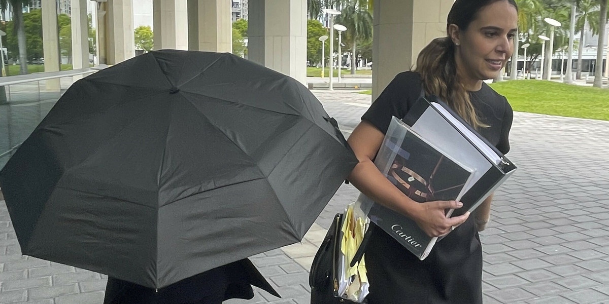 Projektantka Nancy Gonzalez ukrywa się pod parasolem, idąc ze swoją prawniczką do sądu, 22 kwietnia 2024 r., Miami
