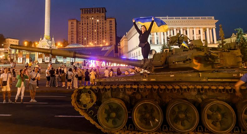 A girl with Ukrainian flag stands on a destroyed Russian tank during an exhibition destroyed Russian military vehicles on Khreshchatyk street in center of Kyiv, Ukraine, August 20, 2022.
