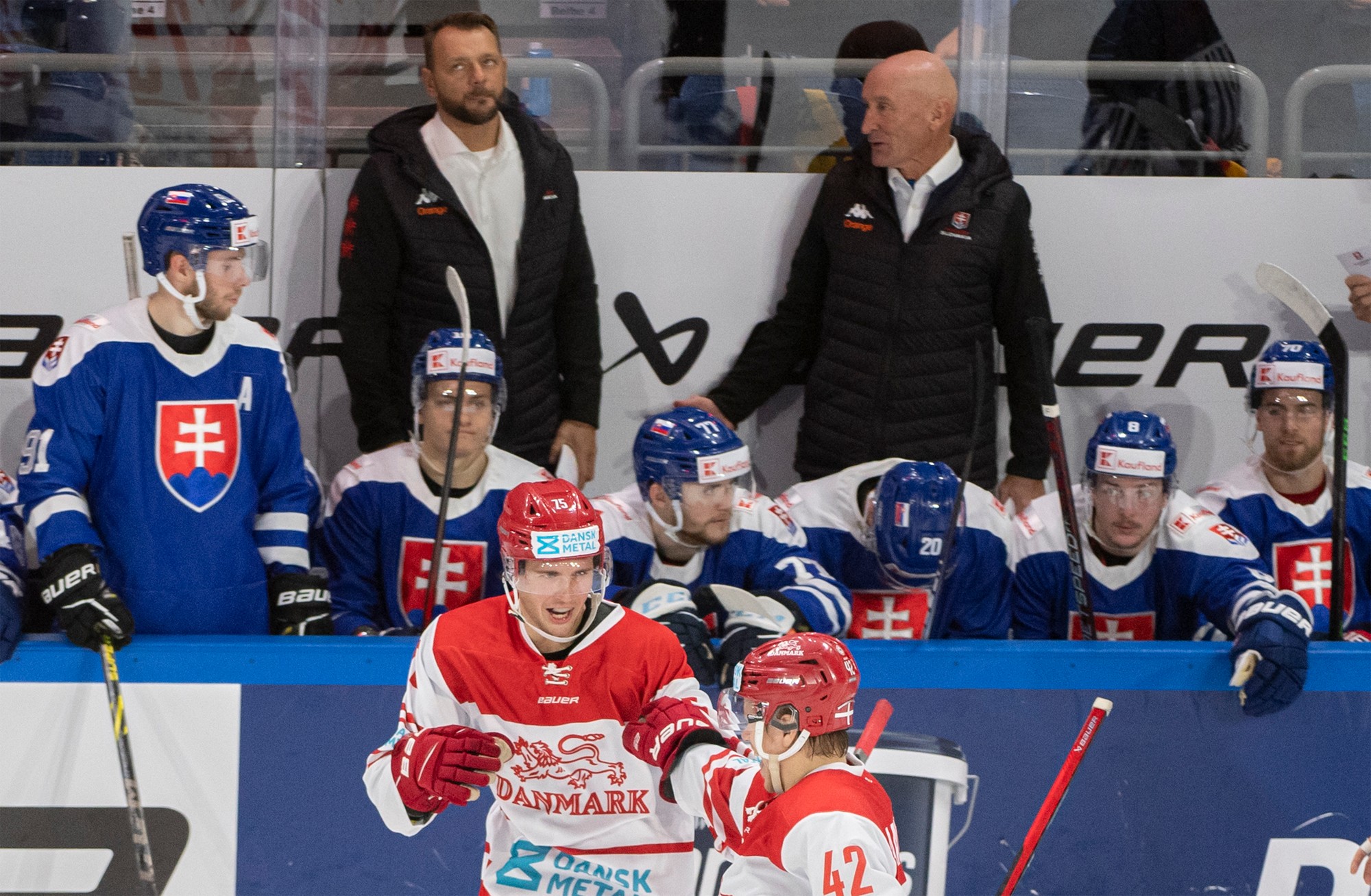 V pozadí reakcia slovenskej striedačky, vpravo hore tréner slovenských hokejistov Craig Ramsay, vľavo hore jeho asisitent Andrej Podkonický.