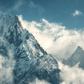 Manaslu mountain with snowy peak in clouds in sunny bright day in Nepal. Landscape with high snow covered rocks and blue cloudy sky. Beautiful nature. Fairy scenery. Aerial view of Himalayan mountains