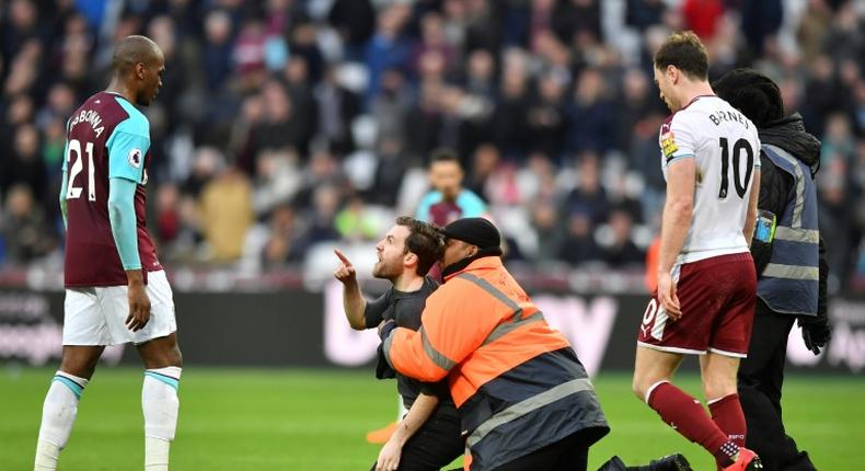 A pitch invader gestures at West Ham United's Angelo Ogbonna (left) during crowd trouble at a Premier League match against Burnley in March