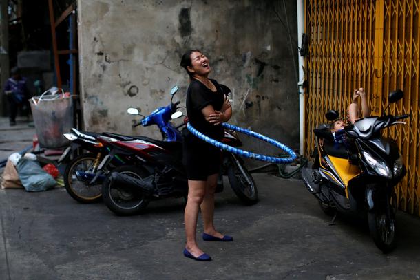 A woman plays with a hula hoop outside her house in Chinatown, Bangkok
