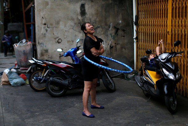 A woman plays with a hula hoop outside her house in Chinatown, Bangkok