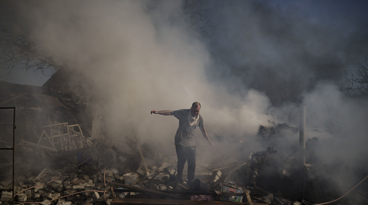 Égő ház romjai között megy egy férfi. / Fotó: MTI/AP/Felipe Dana