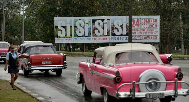 Cars in Havana pass a sign calling for a yes vote in the referendum on Cuba's new Constitution