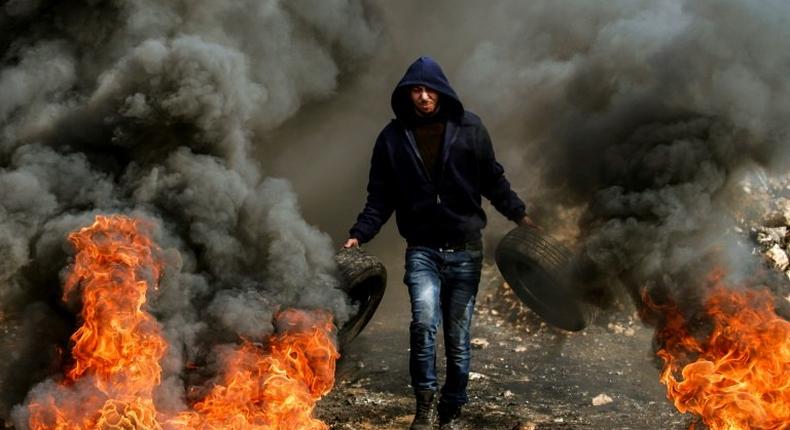 A Palestinian protester burns car tyres during clashes with Israeli security forces near Nablus, in the occupied West Bank, on January 13, 2017